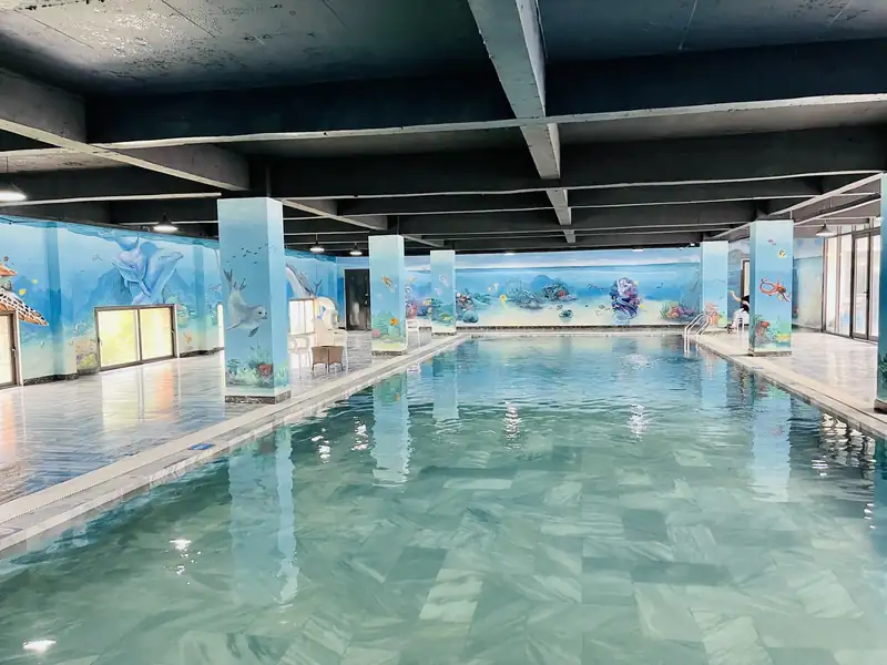 Lòng bể bốn mùa vắng khách nhìn dọc, hàng cột vẽ tranh, cửa kính lớn một bên và trần tối màu