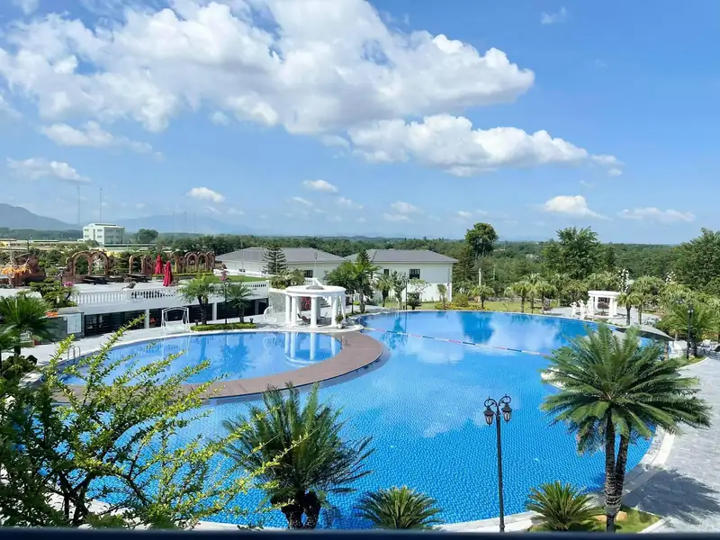 Bể bơi ngoài trời Glory Resort lòng cong giữa hàng cọ, nhìn từ trên cao ra đồi xanh