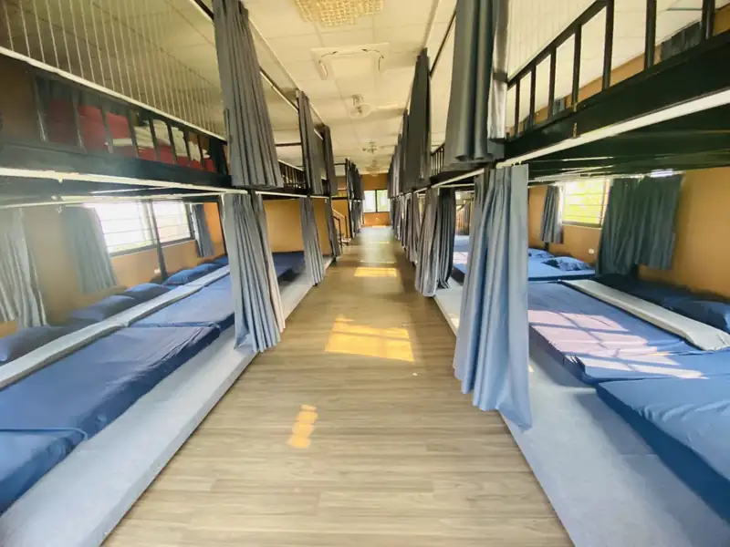 Phòng cộng đồng tiêu chuẩn hai tầng sạp nằm, rèm che từng dãy, lối đi lát sàn gỗ ở giữa