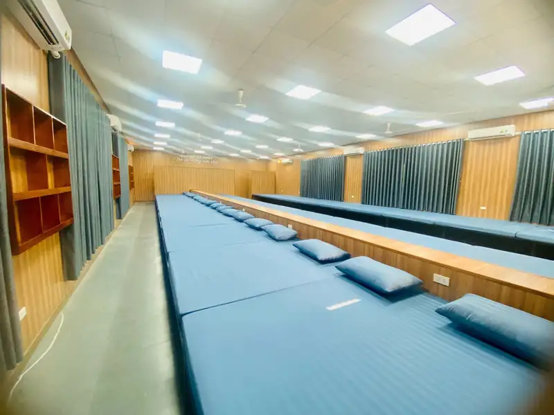 Phòng cộng đồng VIP cho đoàn: hai dãy sạp nằm trải đệm xanh, gối, kệ gỗ và cửa sổ rèm