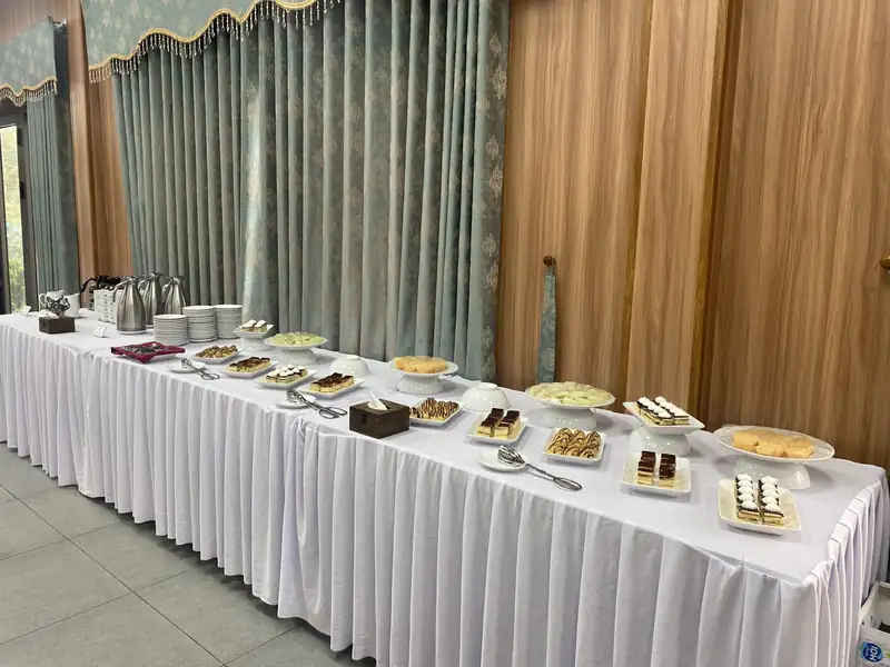 Bàn teabreak trải khăn trắng xếp bánh ngọt, trái cây và bình trà cà phê ở Hội trường 3
