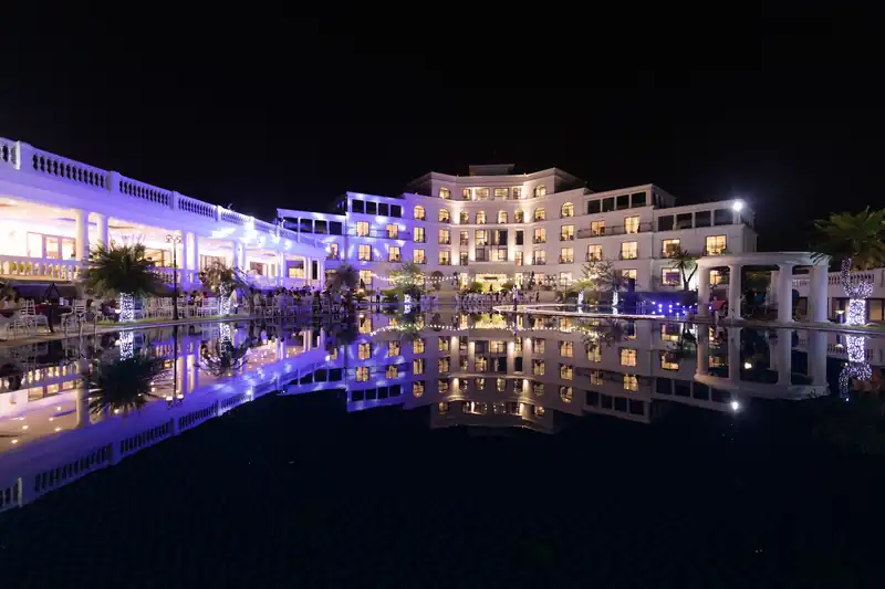 Glory Resort về đêm: dãy nhà trắng lên đèn tím vàng, soi bóng xuống mặt hồ phẳng lặng