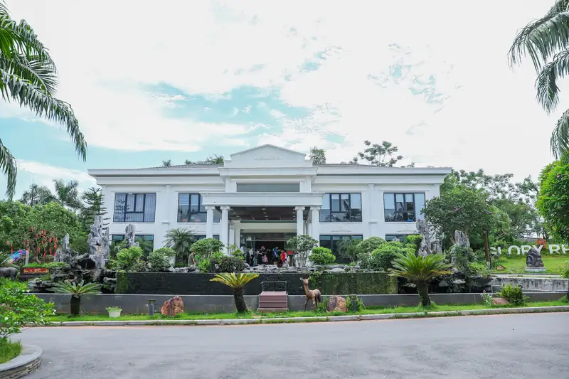 Nhà điều hành Glory Resort mặt tiền trắng, hàng cột và mái tam giác, phía trước là non bộ và cây cảnh