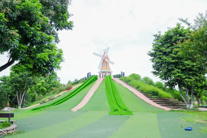 Đồi trượt cỏ Glory Farm với ba máng trượt xanh và cối xay gió trắng trên đỉnh, hai bên là cây xanh