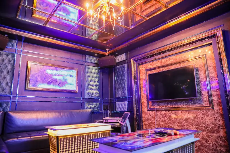 Phòng karaoke ánh tím, sofa da, màn hình lớn và trần gương với đèn chùm