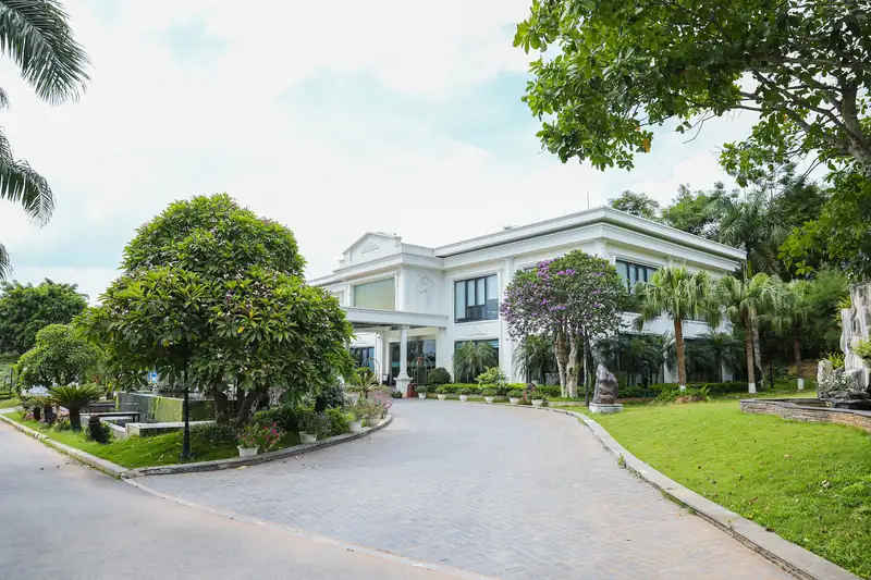 Lối xe lát đá vào nhà điều hành Glory Resort, nơi làm thủ tục nhận phòng, hai bên cây hoa và bãi cỏ