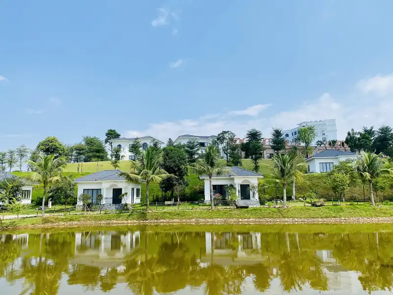 Dãy LakeSide Villa của Glory Resort mái ngói xám nằm sát bờ hồ, phía sau là đồi cỏ