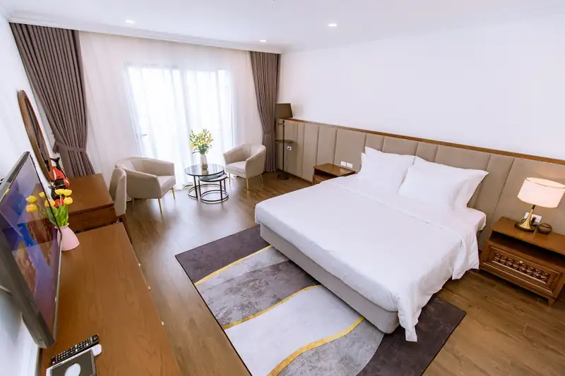 Phòng Deluxe King Pool View giường lớn, thảm xám, cửa kính ban công cuối phòng