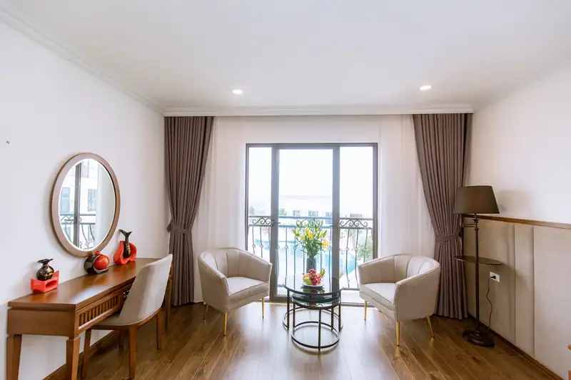 Góc ngồi cạnh cửa ban công phòng Pool View: bàn trà, đôi ghế bành, bàn trang điểm và đèn cây