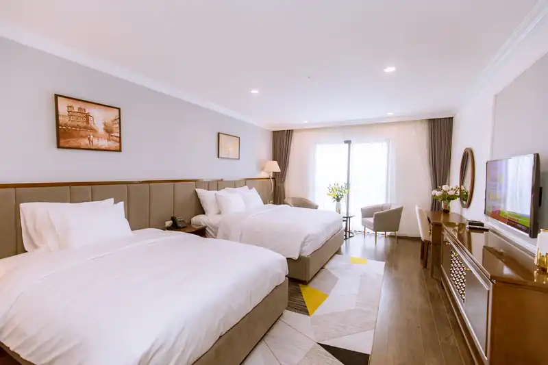 Phòng Deluxe Twin Pool View hai giường trắng, bàn làm việc và cửa kính đón nắng