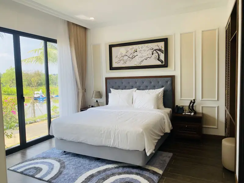 Phòng ngủ LakeSide Villa giường lớn đầu bọc nỉ, cửa kính kịch trần nhìn ra vườn