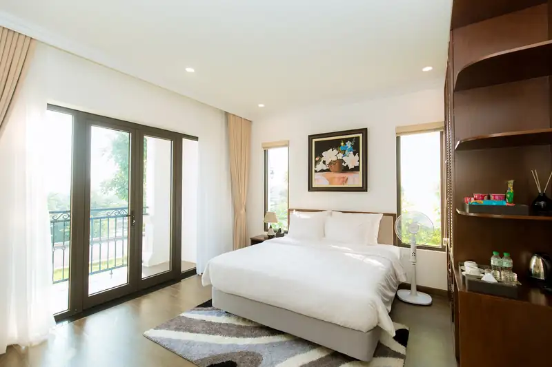 Một phòng ngủ Osaka Villa: giường lớn, thảm, cửa kính ra ban công và kệ gỗ