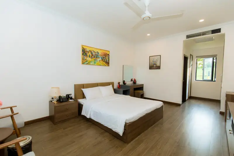 Phòng Standard 1G Garden: giường đôi 1,6 m trải ga trắng, tủ đầu giường gỗ, tranh phố cổ treo tường