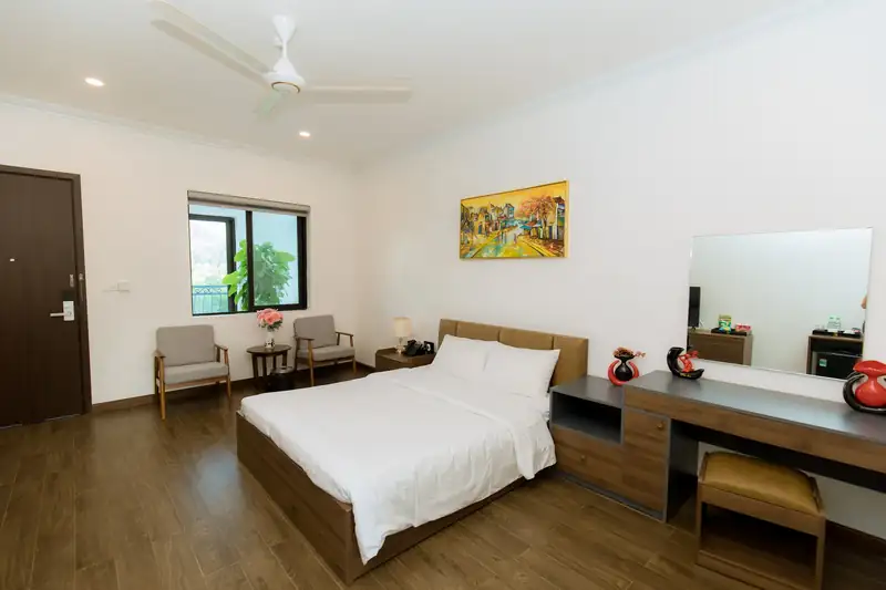 Phòng Standard 1G Garden nhìn từ góc giường: bàn trang điểm, đôi ghế bành cạnh cửa sổ và cửa ra vào
