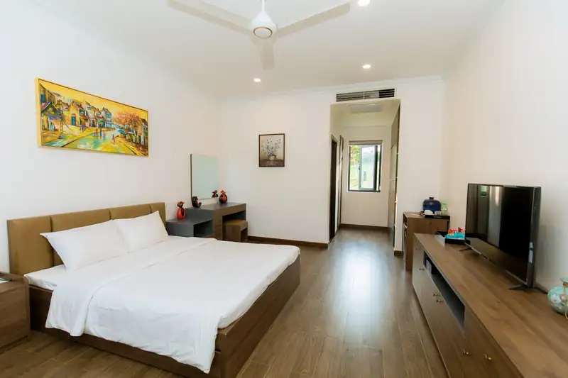 Phòng Standard 1G Garden với kệ ti vi gỗ dài đối diện giường, sàn gỗ và quạt trần