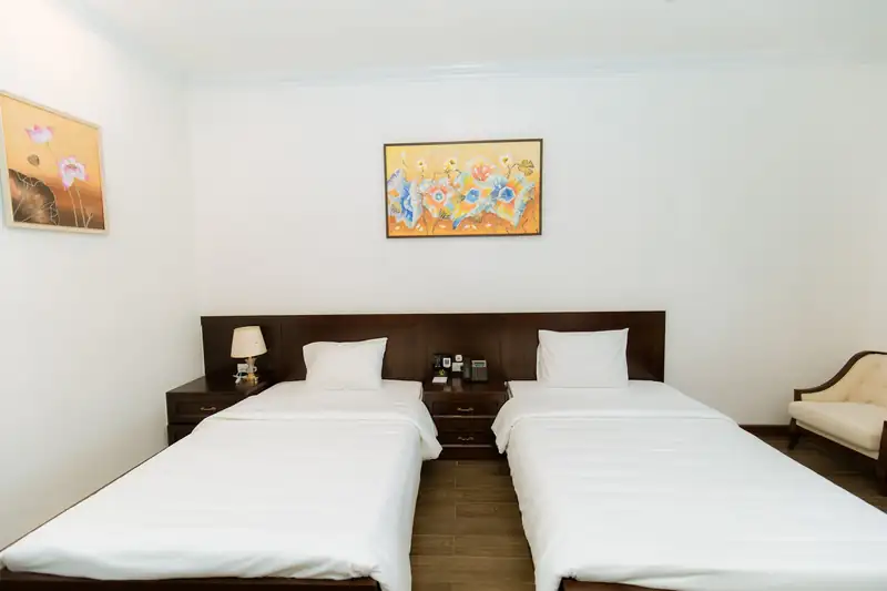 Phòng Standard 2G Garden hai giường đơn kê song song, đầu giường gỗ tối màu, tranh hoa phía trên