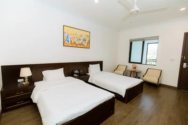 Phòng Standard 2G Garden: hai giường cạnh nhau, đôi ghế bành và cửa sổ nhìn ra cây xanh