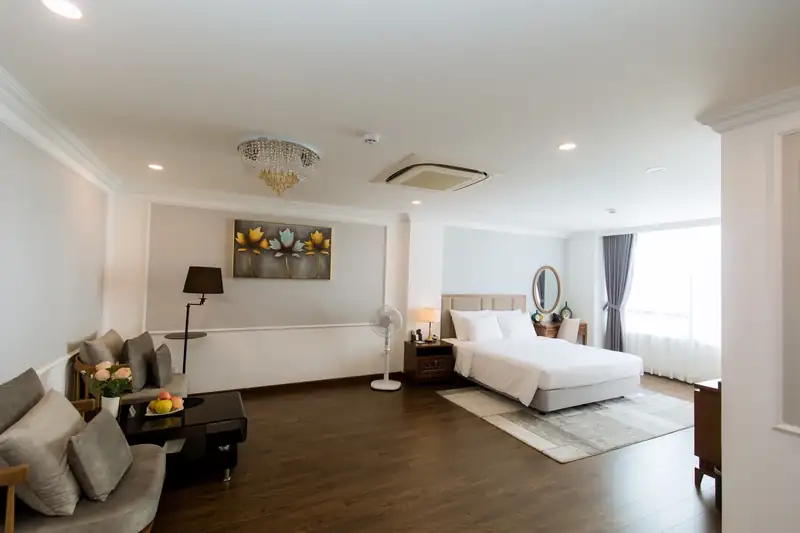 Phòng Suite Pool View rộng với sofa tiếp khách, đèn chùm pha lê và giường đôi cạnh cửa kính