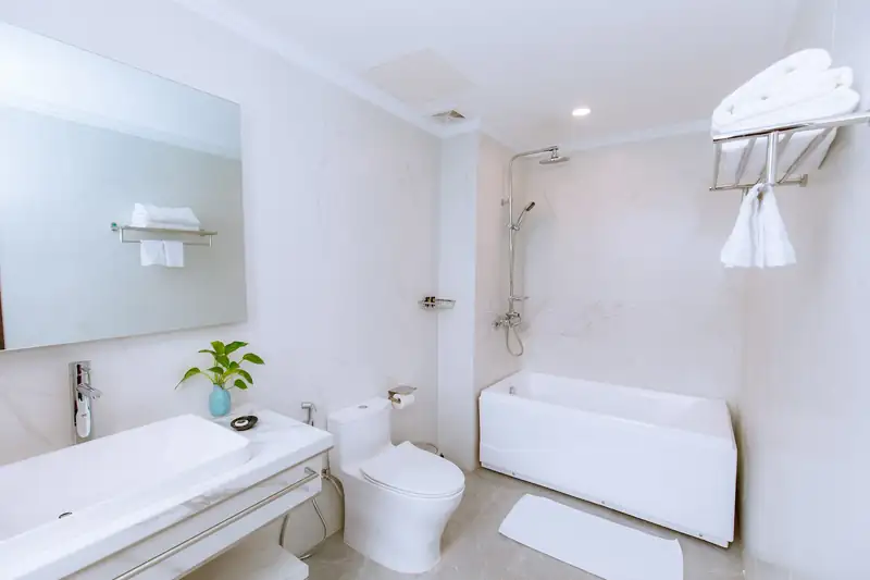 Phòng tắm hạng Suite Pool View với bồn tắm trắng, lavabo đá và gương lớn