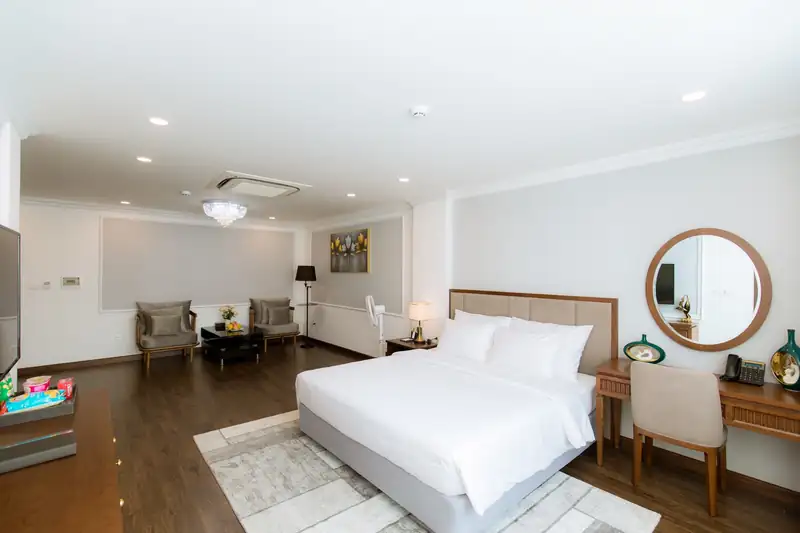 Phòng Suite Pool View: giường đôi, thảm, bàn trang điểm gương tròn và góc sofa phía xa