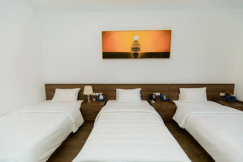 Phòng Triple Garden ba giường đơn kê hàng ngang dưới bức tranh hoàng hôn cam