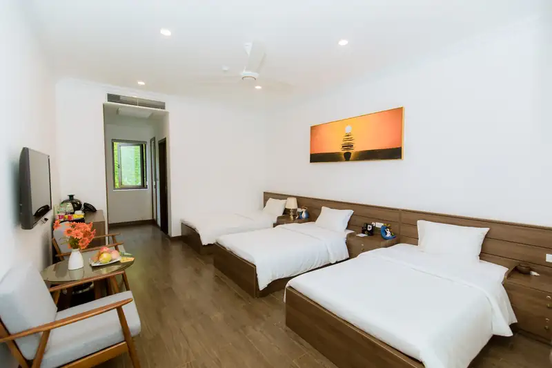 Phòng Triple Garden nhìn dọc phòng: ba giường, ghế bành, bàn trà và ti vi treo tường
