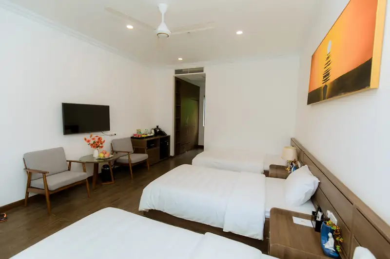 Góc phòng Triple Garden: đôi ghế bành, bàn nhỏ và ti vi đối diện ba giường