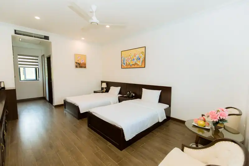 Phòng hai giường khu Garden tại Glory Resort, sàn gỗ, ghế bành và tranh hoa treo tường