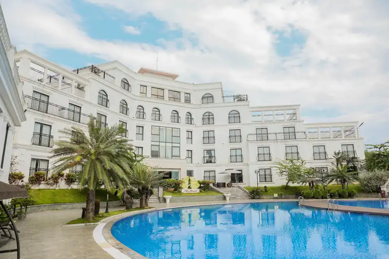 Tòa nhà Pool View nhìn từ bờ bể bơi lòng cong, hàng cọ và trời mây trắng
