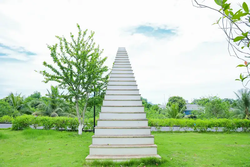 Nấc thang Thiên đường trắng dựng giữa bãi cỏ xanh, trời mây sáng phía sau